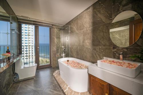 岘港Golden Lotus Luxury Hotel Danang的浴室设有2个水槽、浴缸和镜子