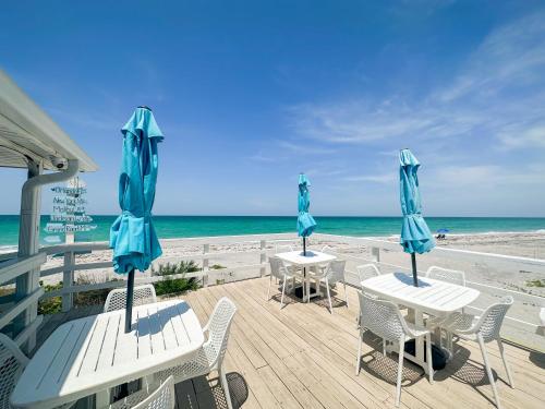 恩格尔伍德The Pearl Beach Inn的海滩上的两张桌椅和遮阳伞