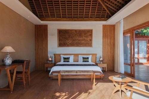 BumbangTUNAK Resort Lombok的卧室配有一张床和一张桌子及椅子