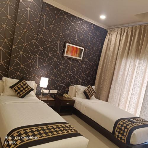班加罗尔ASTRA HOTELS & SUITES WHITEFIELD NEAR TO NALLURAHALLI METRO STATION and KTPO的酒店客房带两张床和一面墙
