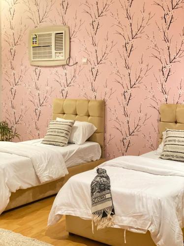 欧拉فيلا بمسبح وحديقة خاصة的配有粉红色壁纸的客房内的两张床