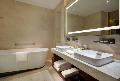 丽江丽江实力希尔顿花园酒店的浴室设有2个水槽、浴缸和镜子