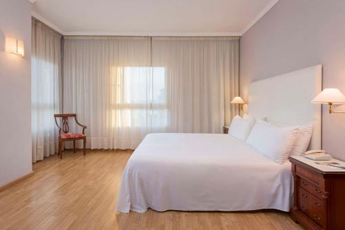 梅利利亚Hotel Melilla Puerto, Affiliated by Meliá的卧室配有一张白色大床和一把椅子