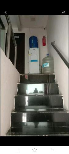 孟买Royal Orchid'S AC Dormitory的客房内的一套楼梯和一瓶水