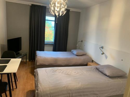 雪平Vandrarhem Köping的客房设有两张床、一张桌子和一个吊灯。
