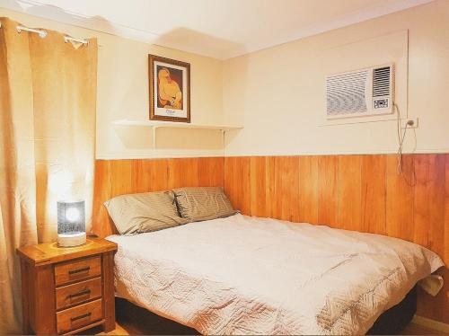 BoulderMain Reef Hotel的一间卧室配有一张床和一张桌子及床头柜