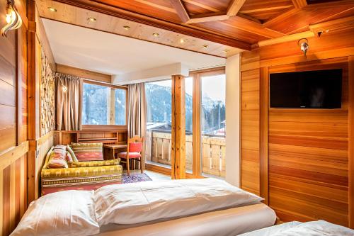 摩德纳迪-坎皮格里奥大湖酒店的一间卧室设有一张床、一台电视和一个阳台。
