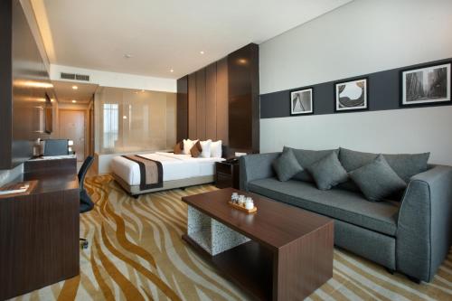 万隆Grand Tjokro Premiere Bandung的酒店客房设有一张沙发和一张床
