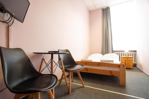 弗罗茨瓦夫Moon Hostel Wrocław的配有床和两把椅子及一张桌子的房间