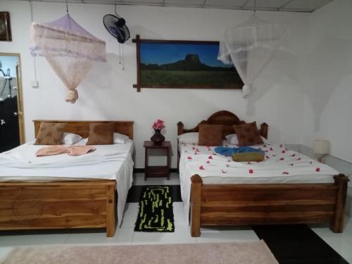 锡吉里亚sigiriya village hostel的一间卧室设有两张床,墙上配有电视。