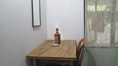 阿努拉德普勒Anuhas Family Resort & Water House的一张木桌,上面装有一瓶和一杯