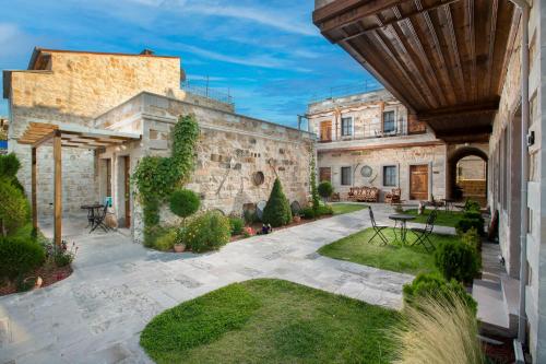 乌奇希萨尔Woox Cappadocia的一个带石头建筑和草地的户外庭院