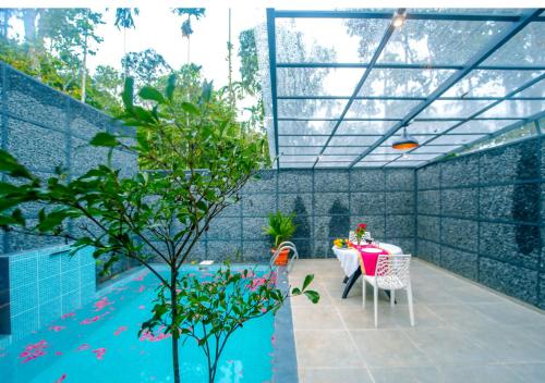 瓦亚纳德Wildside Jungle Retreat Wayanad Resort by VOYE HOMES的一个带桌子和游泳池的庭院