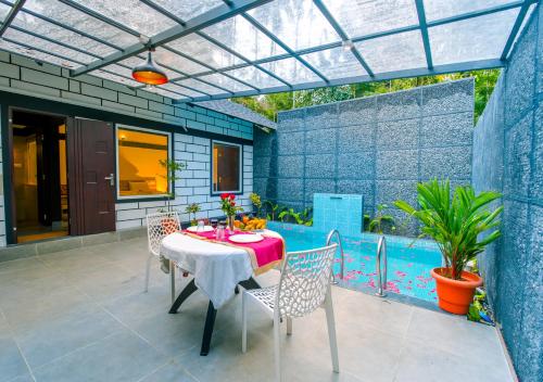 瓦亚纳德Wildside Jungle Retreat Wayanad Resort by VOYE HOMES的一个带桌椅的庭院和一个游泳池
