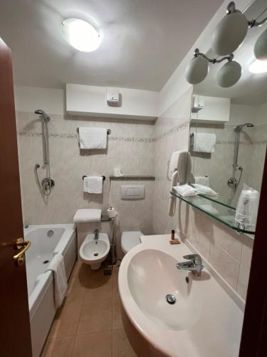 布勒伊-切尔维尼亚Hotel Breuil的浴室配有盥洗盆、卫生间和浴缸。