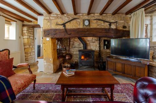 切尔滕纳姆Graziers Cottage - character Cotswold cottage with inglenook, parking and pub nearby的一间带电视和壁炉的客厅