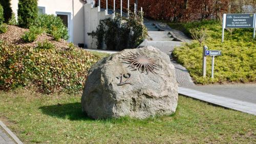 佩尔泽哈肯Villa Sonnenterrasse的一块石头,上面有一张脸,坐在草地上