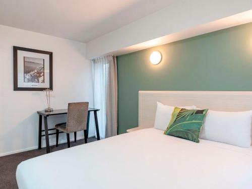 惠灵顿惠灵顿四中心美爵公寓式酒店的配有一张床和一张书桌的酒店客房