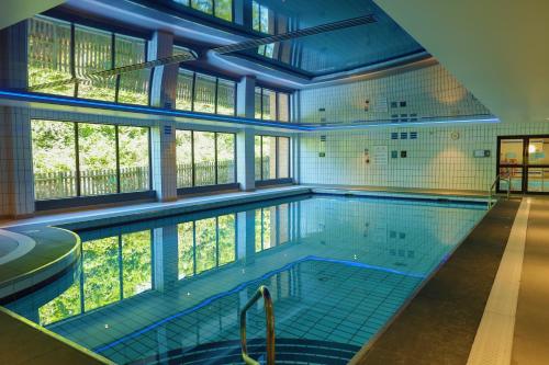 贝辛斯托克Hampshire Court Hotel & Spa的大楼内带大窗户的大型游泳池