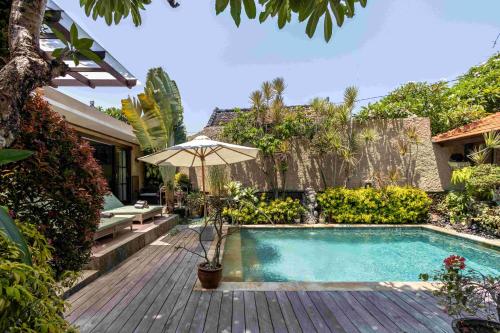 沙努尔Villa Nesanur - Comfortable & Spacious Beachside Sanur的一座房子旁带遮阳伞的游泳池
