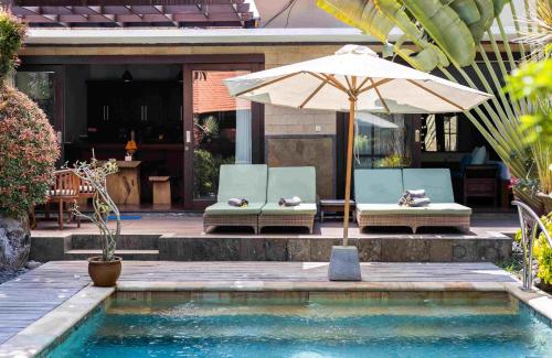 沙努尔Villa Nesanur - Comfortable & Spacious Beachside Sanur的一个带两把椅子和一把遮阳伞的游泳池