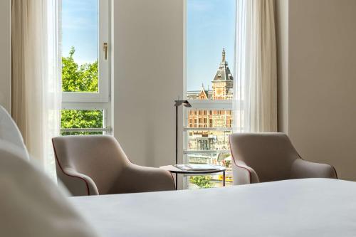 阿姆斯特丹阿姆斯特丹巴比松宫NH酒店的一间设有两把椅子、一张桌子和一个窗户的房间