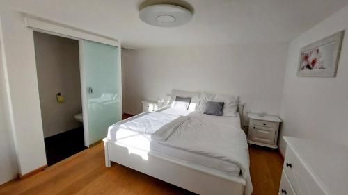 格绍Appartement Twin Peak Edelweiss的一间带白色床的卧室和一间浴室