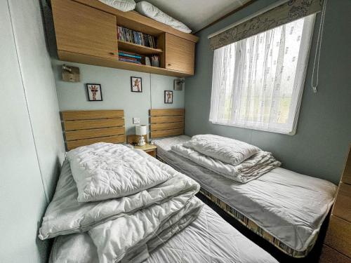 大雅茅斯Great 6 Berth Spacious Caravan With Large Outdoor Space Ref 50056l的配有2张床的小卧室设有窗户