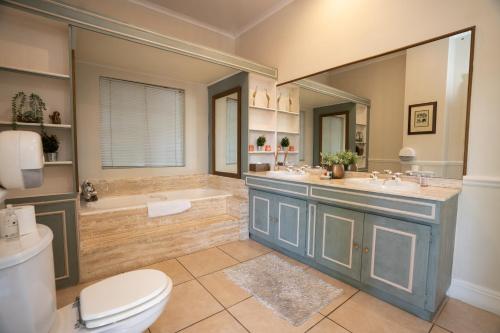 约翰内斯堡小托斯卡纳精品酒店的一间带两个盥洗盆、浴缸和卫生间的浴室