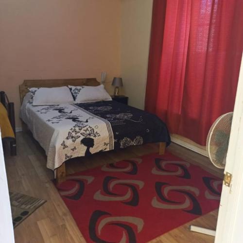 奥瓦列Hotel Arauco Ovalle的一间卧室配有一张床,铺有红色地毯