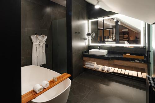 格拉玛多巴伐利亚运动酒店的带浴缸、水槽和镜子的浴室
