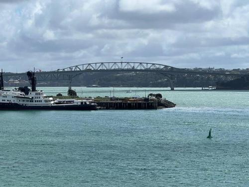 奥克兰Waterfront Seaview Hotel Apartment - same building block as Auckland Hilton的船在水中,在船底下有桥