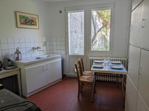 梅斯LES VOLETS BLEUS的厨房配有桌子、水槽和窗户