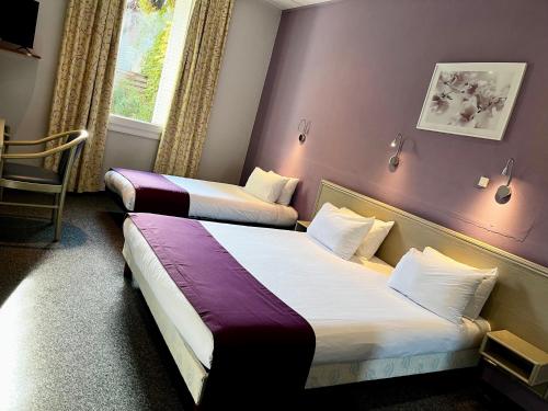 奥朗日CitHôtel Le Louvre的紫色墙壁的酒店客房内的两张床