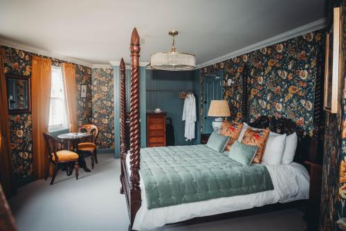 托伯莫里Roslyn House的一间卧室配有天蓬床和花卉壁纸