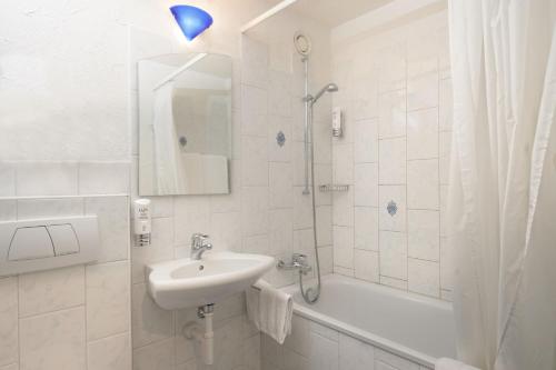 欧普菲康Apart-Hotel Zurich Airport的白色的浴室设有水槽和淋浴。