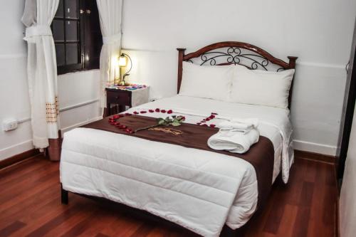 阿亚库乔Casona Valdelirios Hotel的卧室配有一张白色大床,床上有红色的鲜花