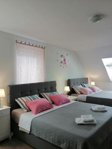 波斯托伊纳Sobe pri Roži的卧室内的两张床和粉红色枕头