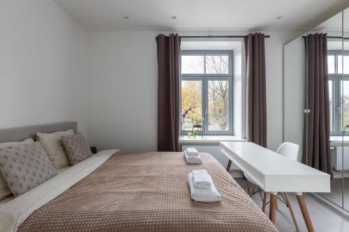 里加Ķīpsala apartments with free parking的一间卧室配有一张床、一张书桌和一个窗户。