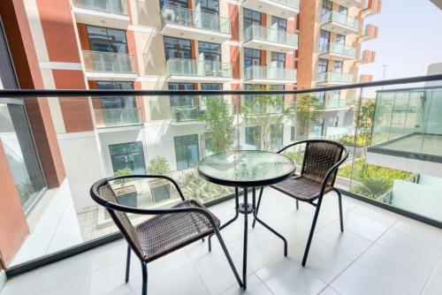 迪拜One Bed Apartment in Dubai - Dubai South - Damac Celestia的阳台配有玻璃桌和两把椅子