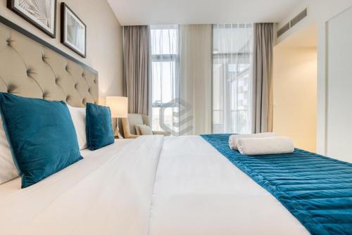 迪拜One Bed Apartment in Dubai - Dubai South - Damac Celestia的卧室配有带蓝色枕头的大型白色床