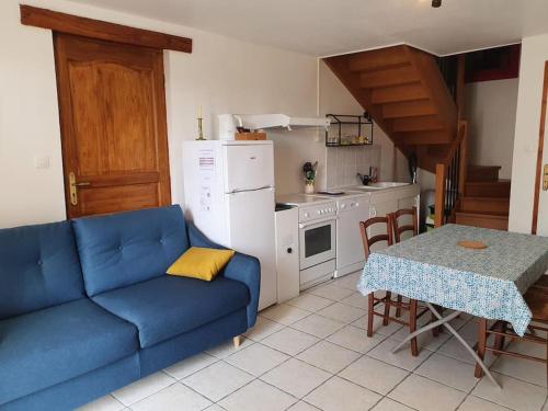 Logement 'la Hulotte'-10 min d'Auxerre-2h de Paris的一间带蓝色沙发的客厅和一间厨房