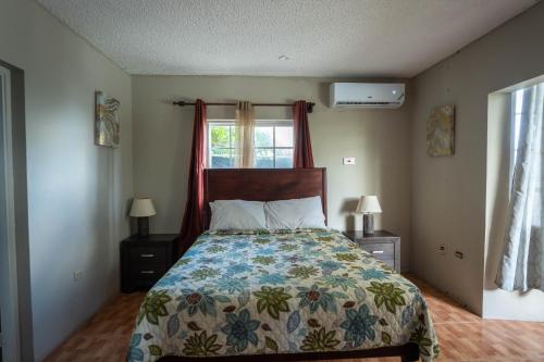 圣玛丽Chrisann's Beach Resort的一间卧室配有一张带花卉床罩的床和窗户。
