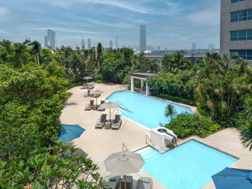 马尼拉Holiday Inn Manila Galleria, an IHG Hotel的享有带椅子和遮阳伞的游泳池的上方景致