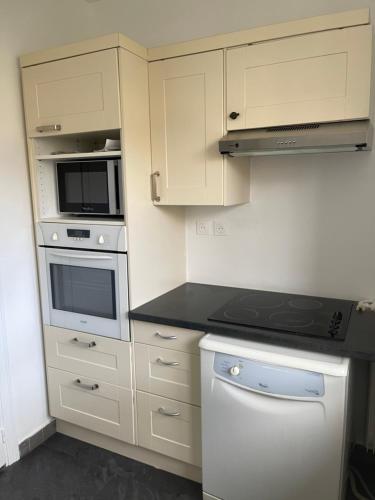 布洛涅-比扬古Appartement neuf à boulogne à 3 mins à pieds du métro的厨房配有白色橱柜和炉灶烤箱。