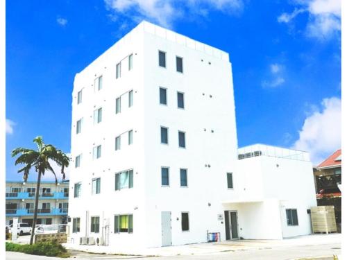 石垣岛HOTEL SANDRIVER ISHIGAKIJIMA - Vacation STAY 91476v的一座白色的建筑,前面有棕榈树