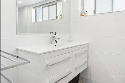 努萨角Absolute Hastings Street Noosa Suite的白色的浴室设有水槽和镜子