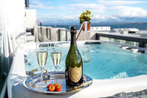 凯夫拉维克Diamond Suites by Reykjavik Keflavik Airport的游泳池旁托盘上的一瓶葡萄酒和玻璃杯