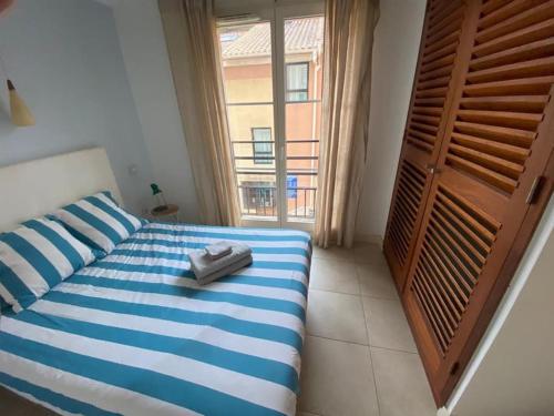 波克罗勒岛Appartement climatisé 50m2 centre du village的卧室配有蓝色和白色的床,设有窗户