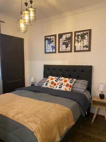 圣地亚哥Hostal El Raco的卧室配有一张床,墙上有三幅照片